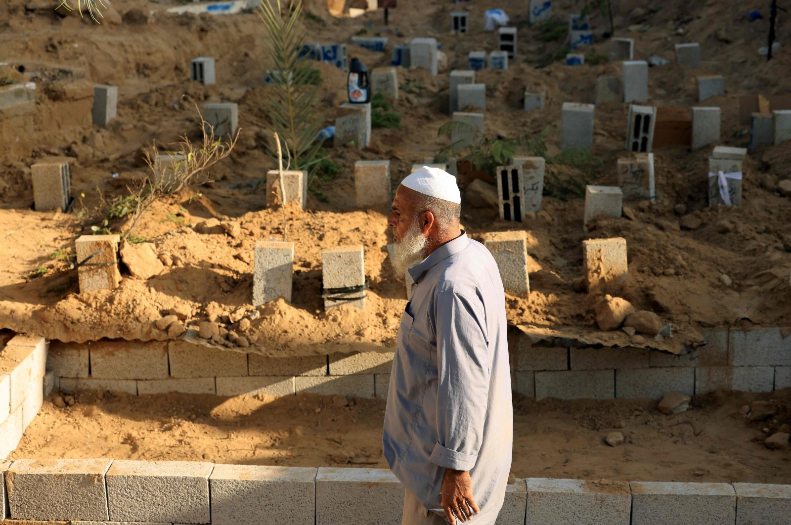 Palestinian grave digger Saadi Hassan Barakeh, 63, walks past breeze blocks used to mark graves at the Deir al-Balah cemetery, Gaza Strip, Palestine, Nov. 10, 2023. (AFP Photo)