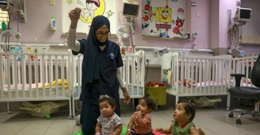 A nurse entertains Palestinian triplets of Gaza-native Hanane Bayouk, Najmeh (L), Najoua (C) and Noor, at the children&#039;s ward of the Al-Maqased Hospital, Jerusalem, Palestine, July 31, 2024. (AFP Photo)