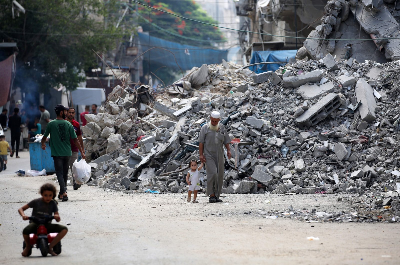 An elderly man holds a child by the hand as he walks past a building levelled by Israeli bombardment in the Bureij refugee camp in central Gaza Strip, Palestine, Aug. 25, 2024. (AFP Photo)