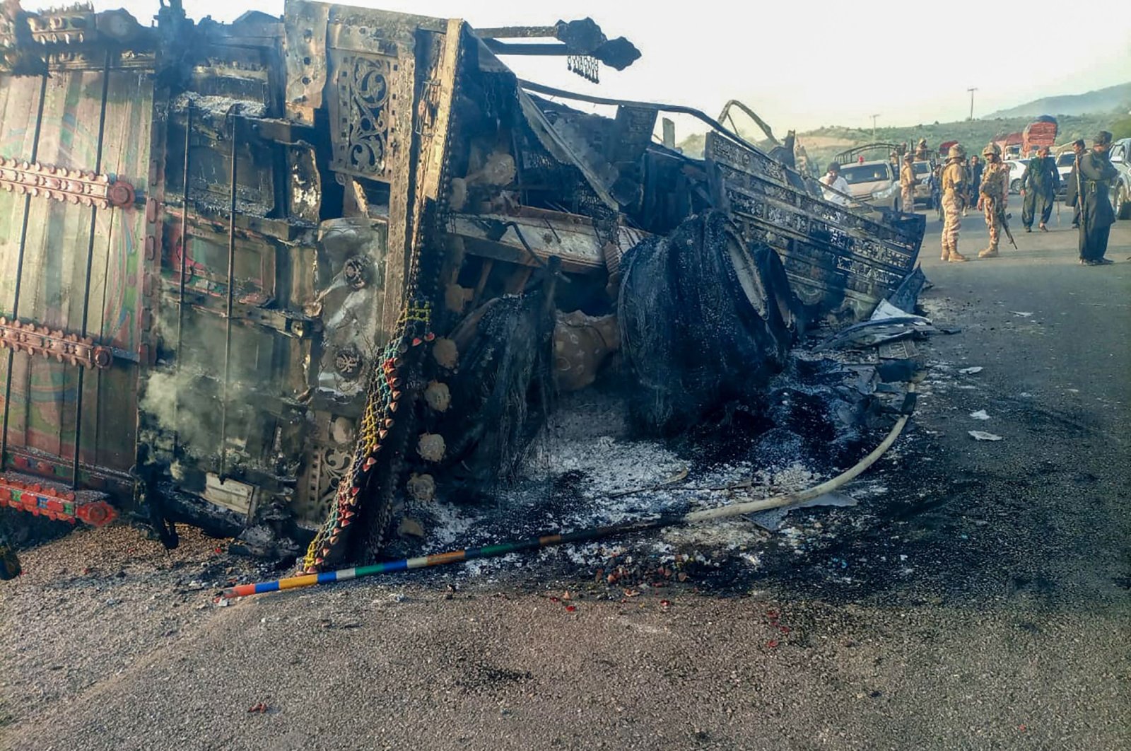 Security personnel stand guard near the charred vehicle at the shooting site on the national highway in the Musakhail district, Balochistan, Pakistan, Aug. 26, 2024. (AFP Photo)