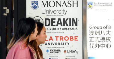 Women walk past signage advertising Australian universities, in Melbourne, Australia, Aug. 27, 2024. (AFP Photo)