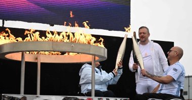 Britain&#039;s Helene Raynsford (L) and Britain&#039;s Gregor Ewan, light the torch of International Paralympic Committee President Andrew Parsons (C), lit from the cauldron, during the Paralympic torch-lighting ceremony at Stoke Mandeville, Aylesbury, U.K., Aug. 24, 2024. (AFP Photo)