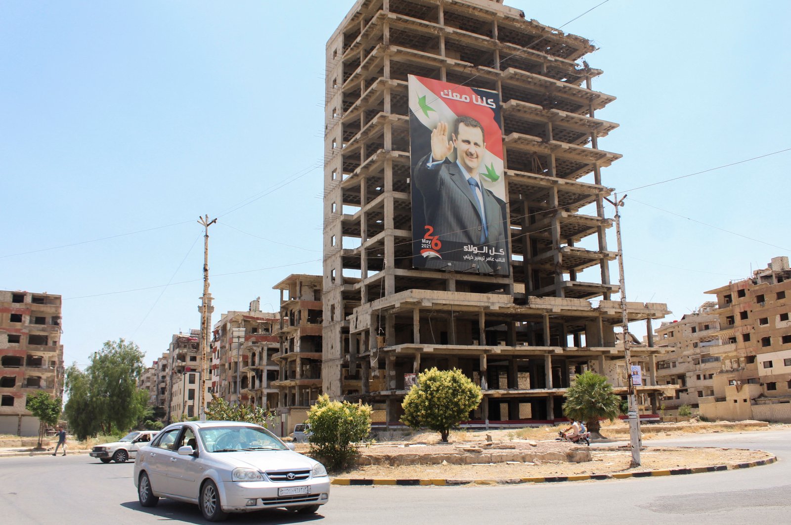 Vehicles pass near a poster depicting Syrian leader Bashar Assad, Douma, Syria, June 19, 2023. (Reuters Photo)