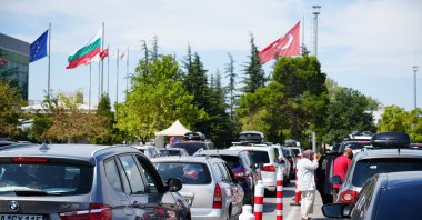 Flags of the European Union, Bulgaria and Türkiye (L to R) are seen in the distance as cars line up to enter Bulgaria through the Kapıkule border gate in northwestern Edirne province, Türkiye, Aug. 25, 2024. (IHA Photo)
