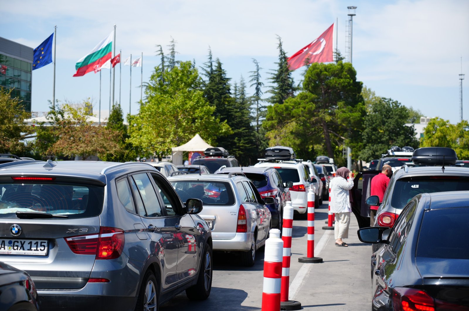 Flags of the European Union, Bulgaria and Türkiye (L to R) are seen in the distance as cars line up to enter Bulgaria through the Kapıkule border gate in northwestern Edirne province, Türkiye, Aug. 25, 2024. (IHA Photo)