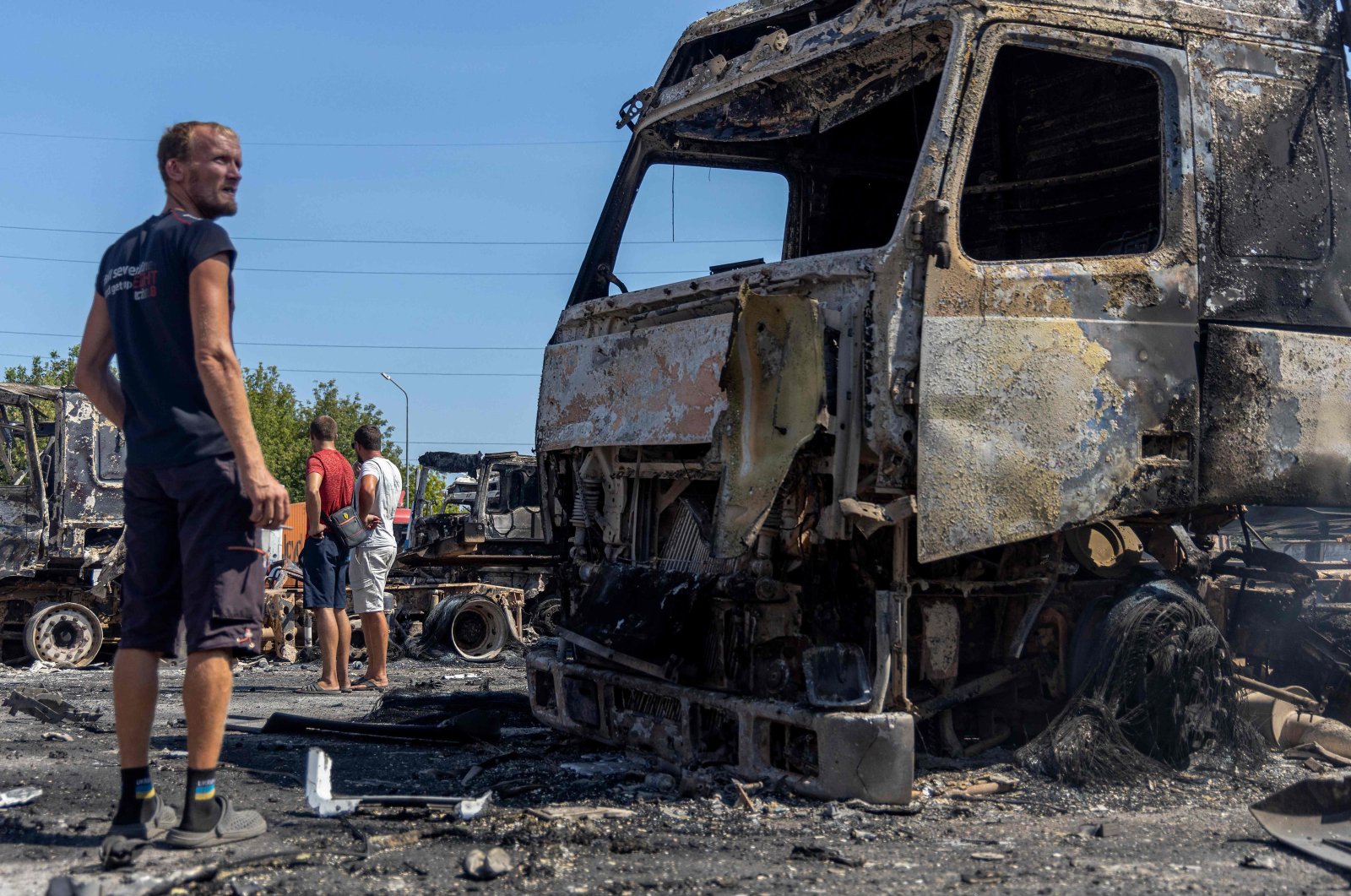 People look at burnt-out trucks on a site following a Russian air attack, in the Odesa region, Ukraine, Aug. 26, 2024. (AFP Photo)