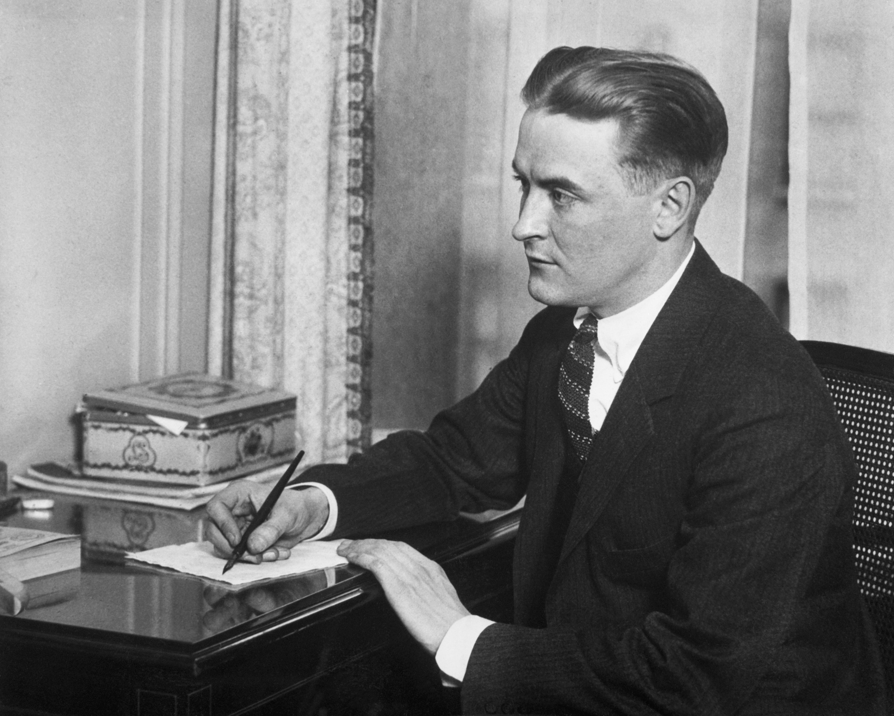 In this undated photo, American writer Scott Fitzgerald is seen sitting at a desk and writing with a pen. (Getty Images photo)