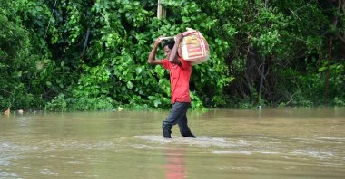 A man carries his belongings through a flooded street after heavy rains on the outskirts of Ahmedabad, India, Aug. 28, 2024. (AFP Photo)