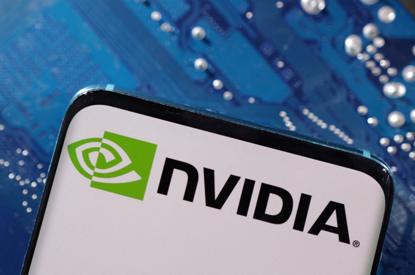 A smartphone with a displayed Nvidia logo is placed on a computer motherboard in this illustration taken on March 6, 2023. (Reuters Photo)