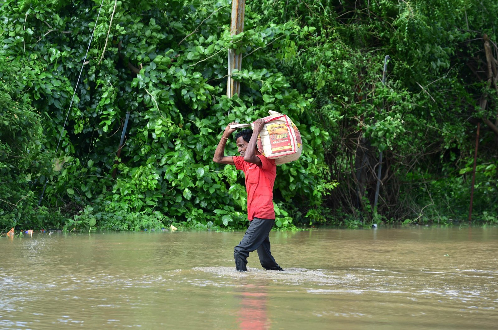 A man carries his belongings through a flooded street after heavy rains on the outskirts of Ahmedabad, India, Aug. 28, 2024. (AFP Photo)