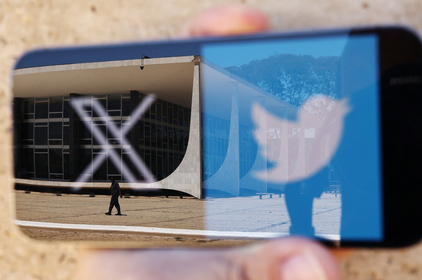 The logo of social media platform X is seen on a mobile phone next to a reflection of Brazil&#039;s Supreme Court in this illustration taken Aug. 30, 2024, in Brasilia, Brazil. (Reuters Photo)