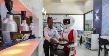 A human waiter is loading a robotic waiter (C) with a food order to deliver to a customer at the Robot Cafe, Kileleshwa, Nairobi, Kenya, Aug. 29, 2024. (EPA Photo)