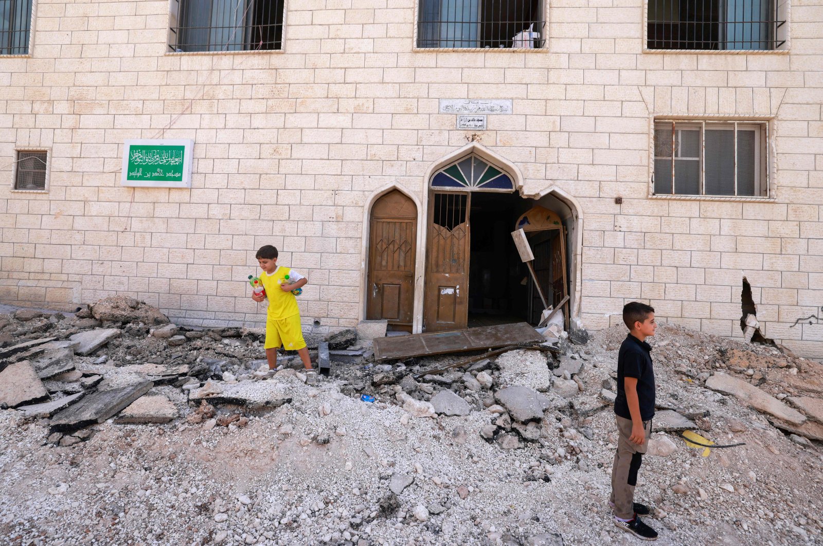 Palestinian boys stand outside a mosque on a street torn up by bulldozers after an Israeli raid, in Jenin, West Bank, occupied Palestine, Sept. 1, 2024. (AFP Photo)