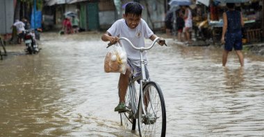 A boy rides his bike through a flooded road with bread and eggs after heavy rains from Tropical Storm Yagi, Rizal, Philippines, Sept. 2, 2024. (Reuters Photo)