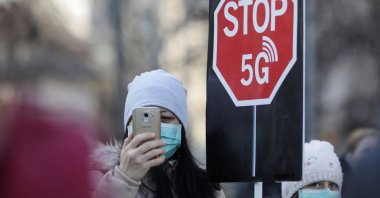 A woman uses her mobile phone while holding a placard reading " STOP 5G" during a protest against 5G technology, in Bucharest, Romania, Jan. 25, 2020. (Reuters File Photo)