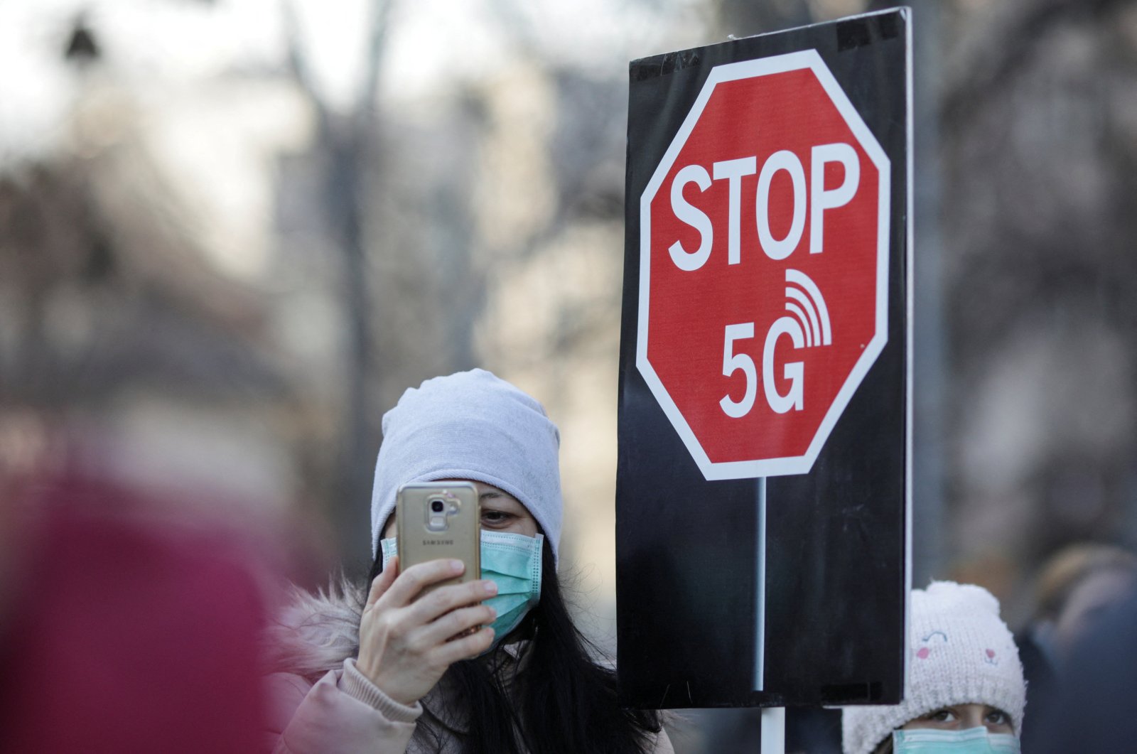 A woman uses her mobile phone while holding a placard reading &quot; STOP 5G&quot; during a protest against 5G technology, in Bucharest, Romania, Jan. 25, 2020. (Reuters File Photo)