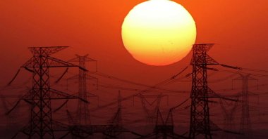 The sun is seen behind high-voltage power lines and electricity pylons along the Cairo-Hurghada desert road, Egypt, July 31, 2024. (Reuters Photo)