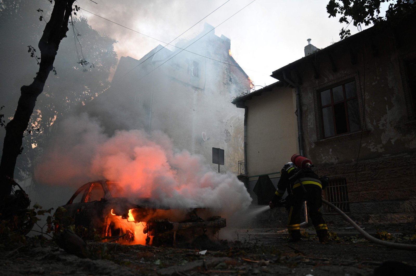 A rescuer works to extinguish a fire in a car following a missile attack in Lviv, Ukraine, Sept. 4, 2024. (AFP Photo)