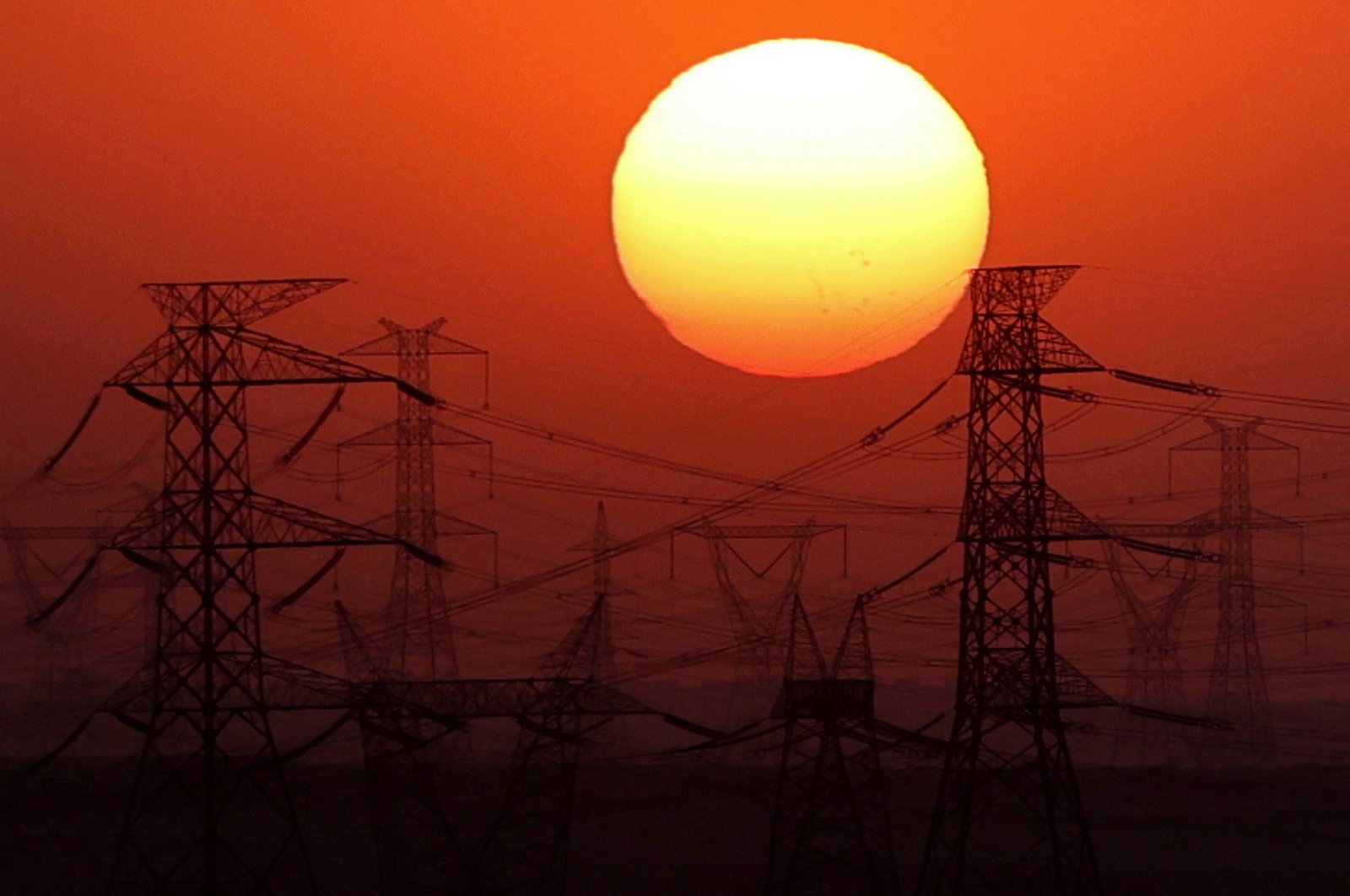 The sun is seen behind high-voltage power lines and electricity pylons along the Cairo-Hurghada desert road, Egypt, July 31, 2024. (Reuters Photo)