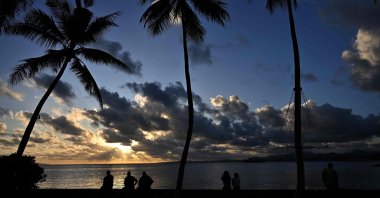 People watch the setting sun along the coast in Suva, Fiji, Dec. 16, 2022. (AFP Photo)