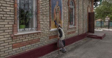 An elderly woman kisses a mural outside a church in the town of Novogrodivka, eastern Donetsk region, Ukraine, Aug. 4, 2024. (AFP Photo)