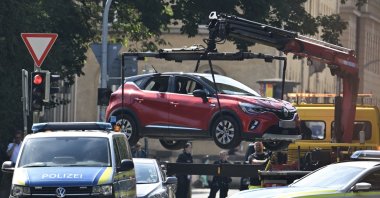 Police officers remove a car with an Austrian plate with a crane as they secure the area after a shooting near the Israeli consulate and the building of the Documentation Centre for the History of National Socialism (NS-Dokumentationszentrum) in Munich, southern Germany, on Sept. 5, 2024. (AFP Photo)