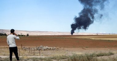 A man watches from afar as a fire rages after a Turkish airstrike at the Zarba oil facility occupied by the PKK/YPG terrorist group, al-Qahtaniyah, Syria, Oct. 5, 2023. (AFP Photo)