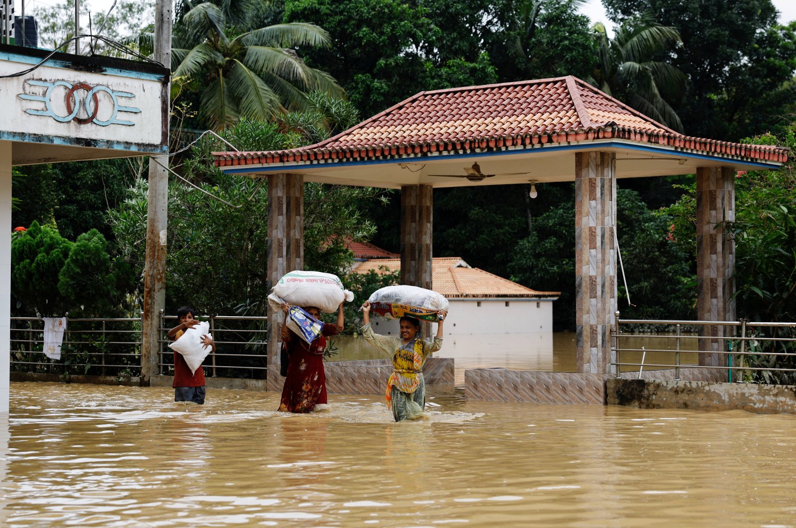 People carrying sacks wade through flood water amid severe flooding in the Fazilpur area of Feni, Bangladesh, Aug. 26, 2024. (Reuters Photo)