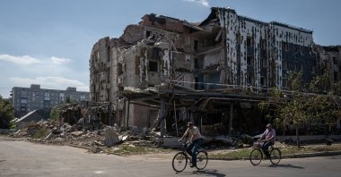 Two men ride bicycles past a building destroyed in Russian attacks on Pokrovsk, Ukraine, Sept. 7, 2024. (AA Photo)