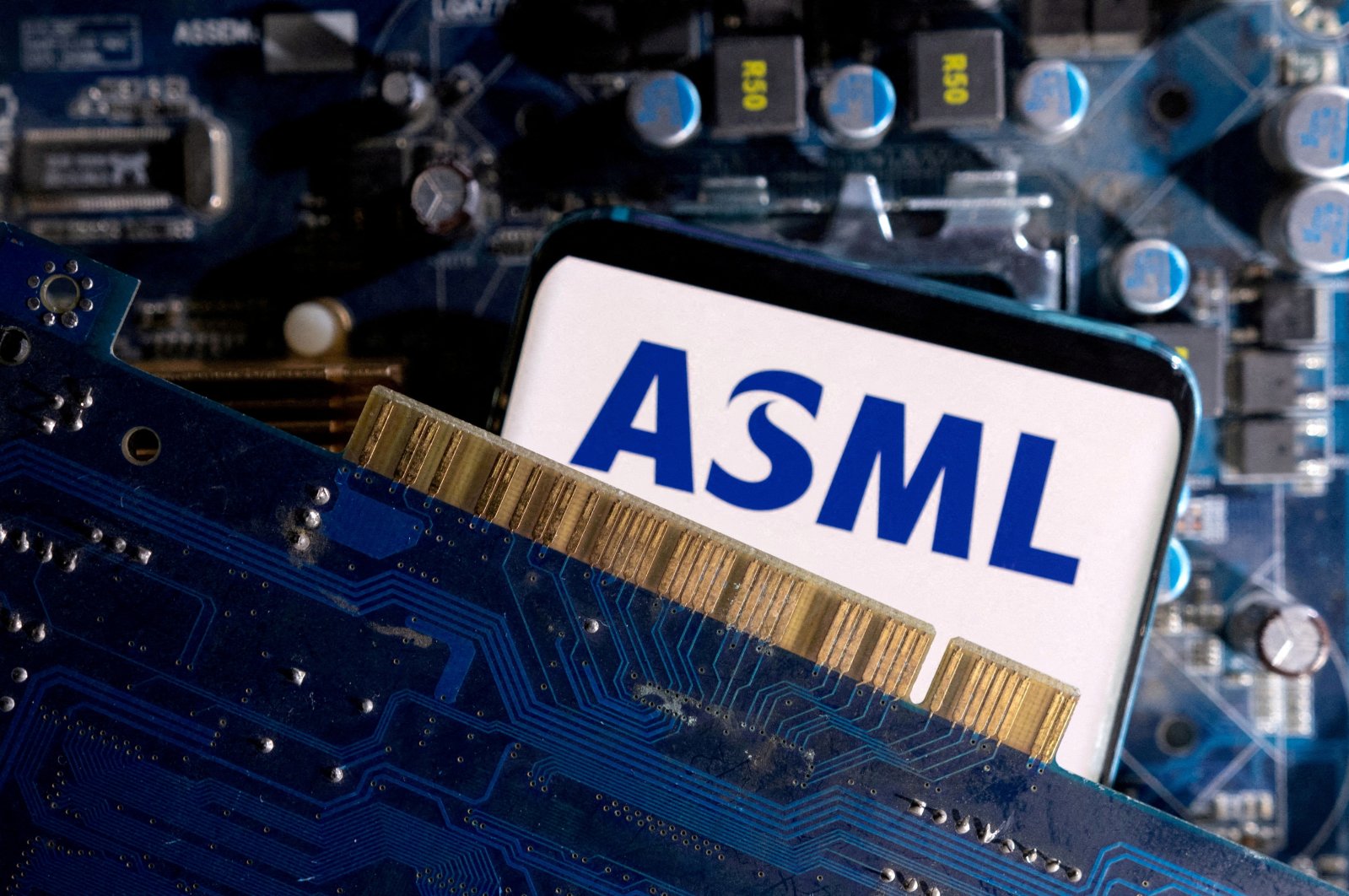 A smartphone with a displayed ASML logo is placed on a computer motherboard in this illustration taken on March 6, 2023. (Reuters Photo)