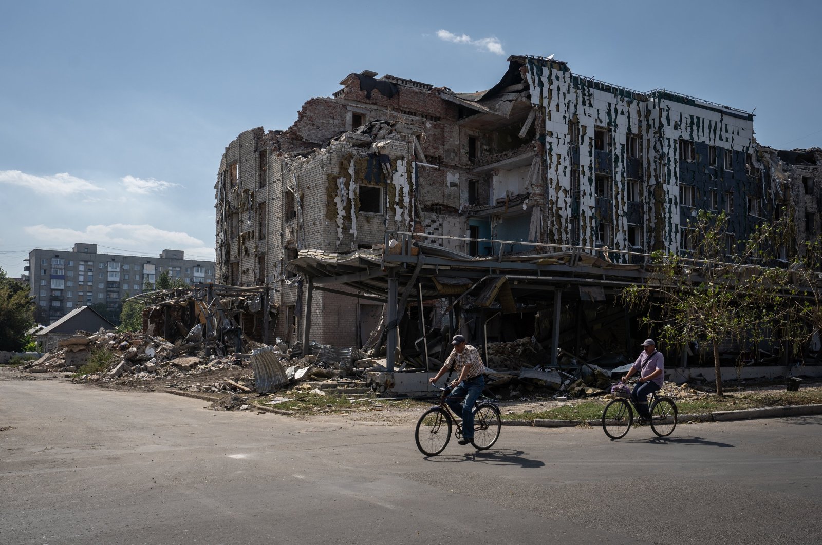 Two men ride bicycles past a building destroyed in Russian attacks on Pokrovsk, Ukraine, Sept. 7, 2024. (AA Photo)