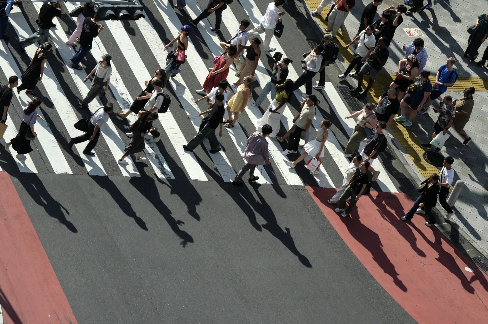 Pedestrians cast shadows on a crosswalk, Tokyo, Japan, Sept. 9, 2024. (EPA Photo)