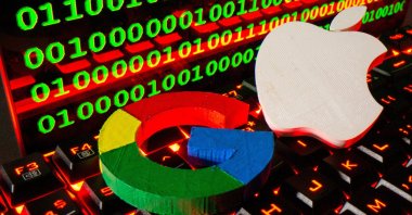 Printed logos of Apple and Google are pictured on a keyboard in front of binary code in this illustration taken on Sept. 24, 2021. (Reuters Photo)