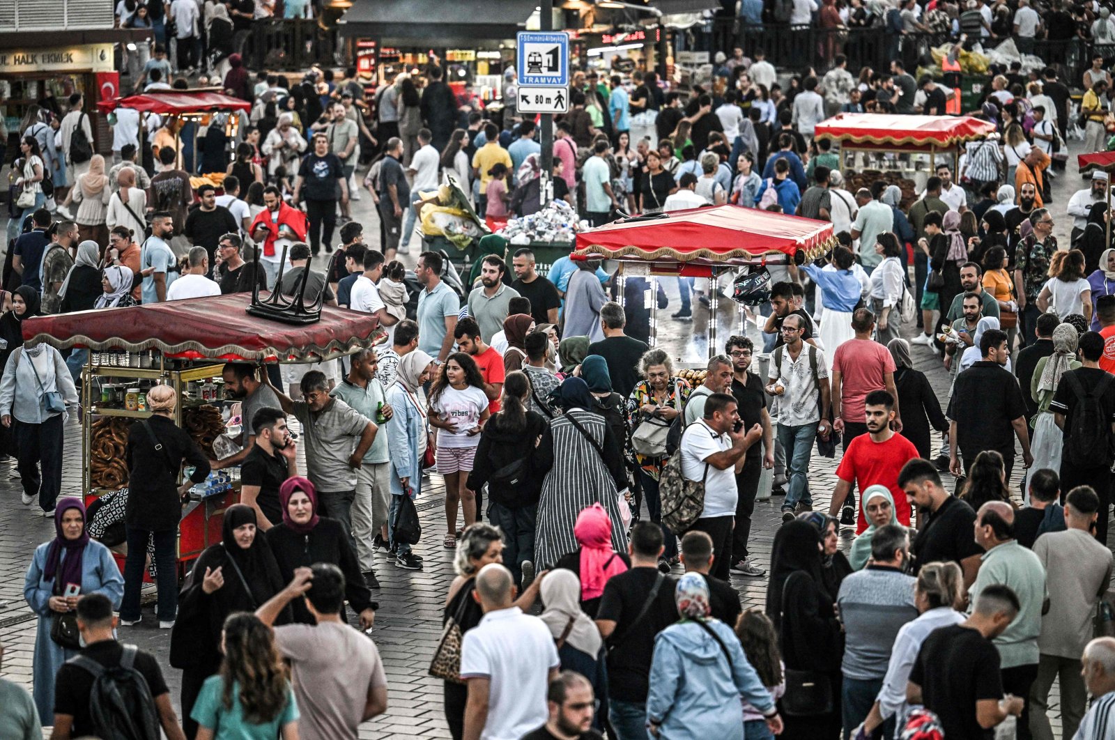 Street vendors sell corn and traditional Turkish-style bagels "simit" as people pass by their stands in the Eminönü area of Istanbul, Türkiye, Aug. 30, 2024. (AFP Photo)