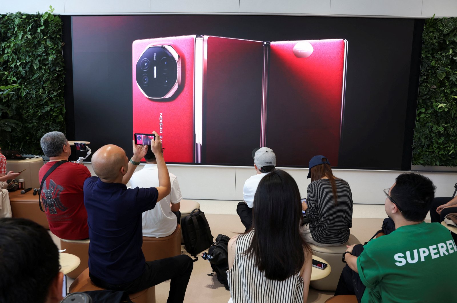 People watch the launch event of Huawei’s new Mate XT, a three-way foldable smartphone, live-streamed at a Huawei flagship store, Beijing, China, Sept. 10, 2024. (Reuters Photo)