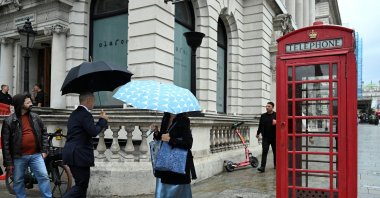 People with umbrellas walk past a phone booth in Westminster, London, U.K., Sept. 10, 2024. (Reuters Photo)