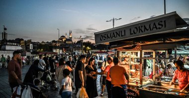 Street vendors sell the traditional sweet "lokma" as people wait in the popular area of Eminönü, Istanbul, Türkiye, Aug. 30, 2024. (AFP Photo)