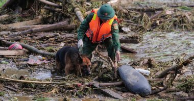 A rescue official works with a dog as they sift through debris at the site of a landslide in Lang Nu, in Lao Cai province, Vietnam, Sept. 12, 2024. (AFP Photo)