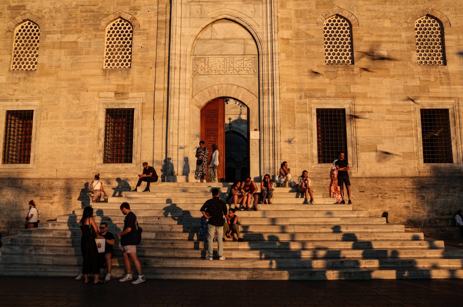 People rest on the stairs of the &quot;Yeni Cami&quot; (New Mosque) in the famous Eminönü neighborhood during sunset in Istanbul, Türkiye, Aug. 15, 2024. (EPA Photo)