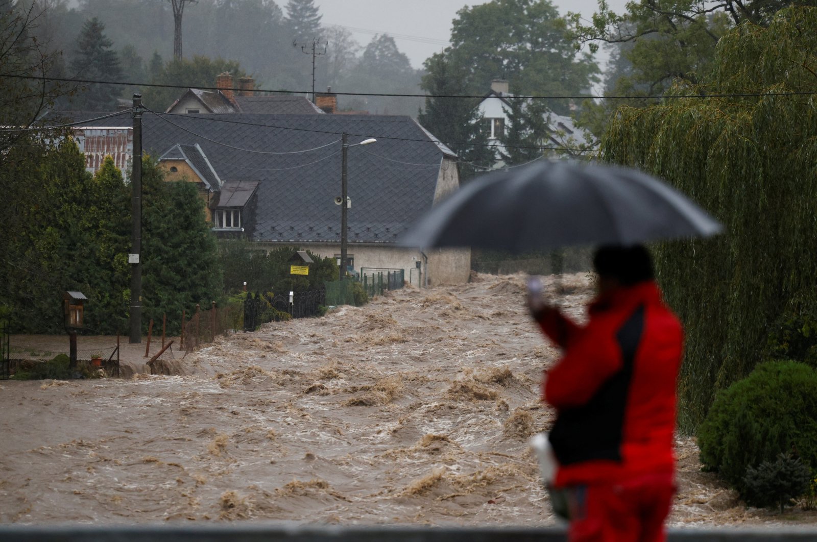 A man stands with an umbrella near a flood-affected area, following heavy rainfall in Lipova Lazne, Czech Republic, September 15, 2024. REUTERS/David W Cerny