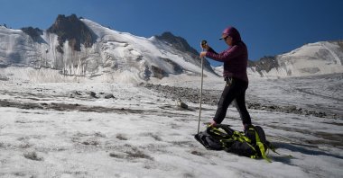 Glaciologist Gulbara Omorova takes measurements of a glacier using an ablation stake in the Tian Shan mountain range, Tian Shan, Kyrgyzstan, July 8, 2024. (AFP Photo)