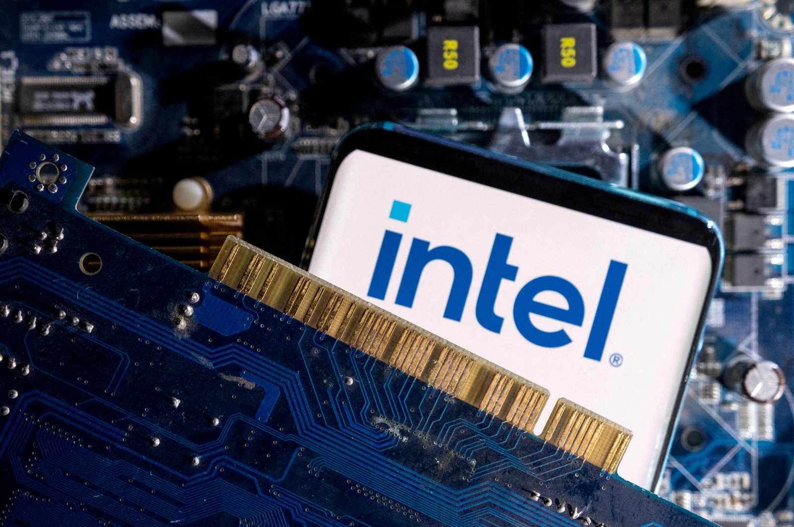 A smartphone with an Intel logo displayed on a computer motherboard is placed in this illustration taken on March 6, 2023. (Reuters Photo)