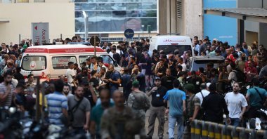  Ambulances are surrounded by people at the entrance of the American University of Beirut Medical Center, Sept. 17, 2024. (AFP Photo)