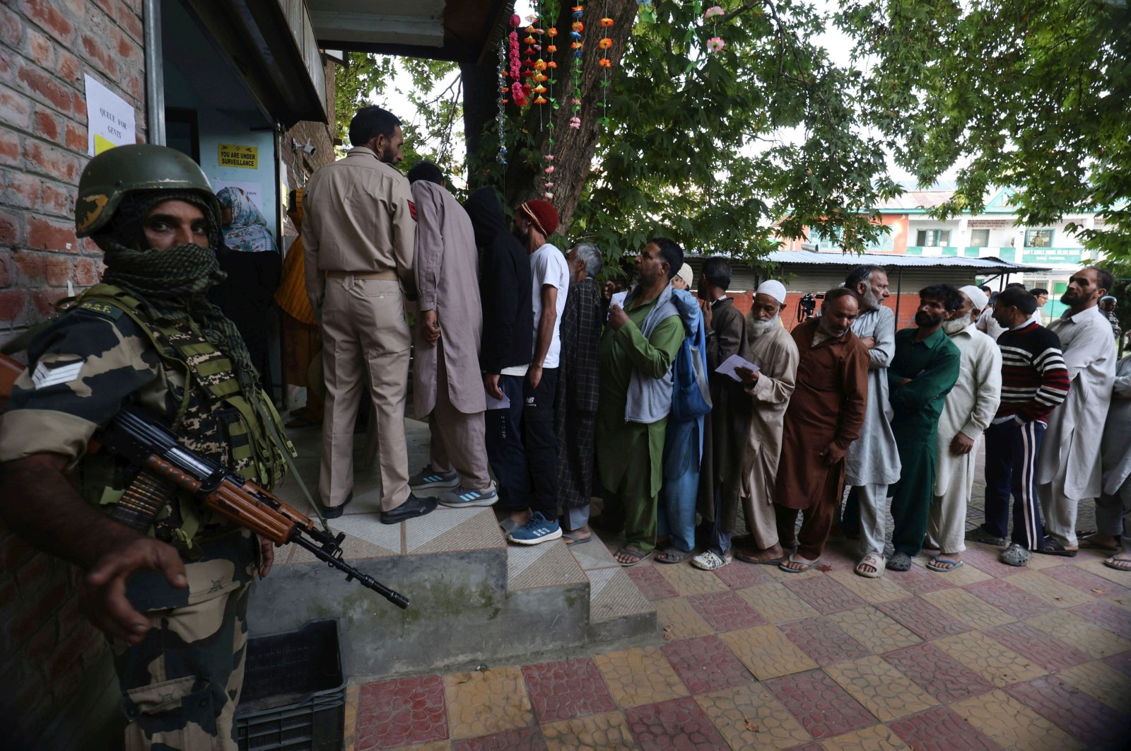 An Indian paramilitary soldier stands guard as voters wait in a queue for local assembly elections, at Naira, southern Kashmir, Sept. 18, 2024. (EPA Photo)