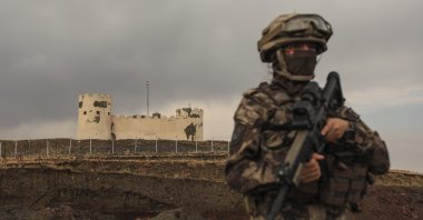 A Turkish soldier stands guard with an Iran security post in the background near the wall that separates Türkiye and Iran, Van province, Türkiye, Aug. 21, 2021. (AP Photo)