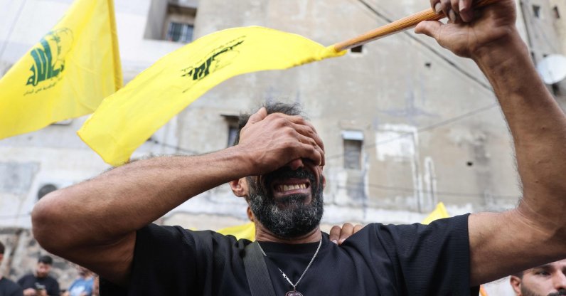 A man reacts while holding a Hezbollah flag during the funeral of people killed after hundreds of paging devices exploded across Lebanon, Sept. 18, 2024. (AFP Photo)