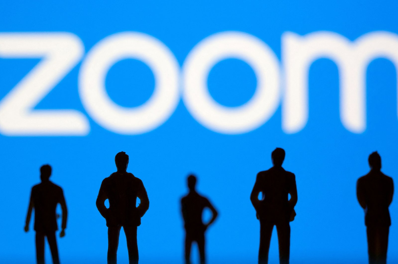 Small toy figures are seen in front of the Zoom logo in this illustration picture taken March 15, 2021. (Reuters Photo)