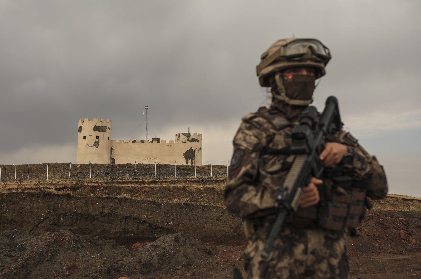 A Turkish soldier stands guard with an Iran security post in the background near the wall that separates Türkiye and Iran, Van province, Türkiye, Aug. 21, 2021. (AP Photo)