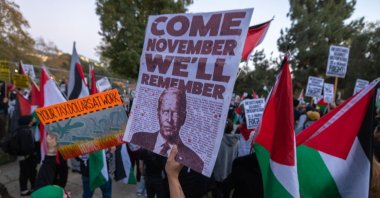 A woman holds a sign suggesting that she might now vote for Donald Trump for president as protesters denounce the Biden administration's support of Israel, which has killed thousands of Palestinian civilians in Gaza, Los Angeles, U.S., Dec. 8, 2023. (Getty Images Photo)