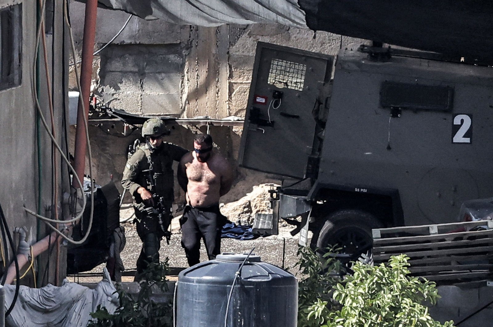 Israeli army soldiers detain a topless blindfolded man during an army raid in Qabatiyah south of Jenin in the occupied West Bank, Palestine, Sept. 19, 2024. (AFP Photo)